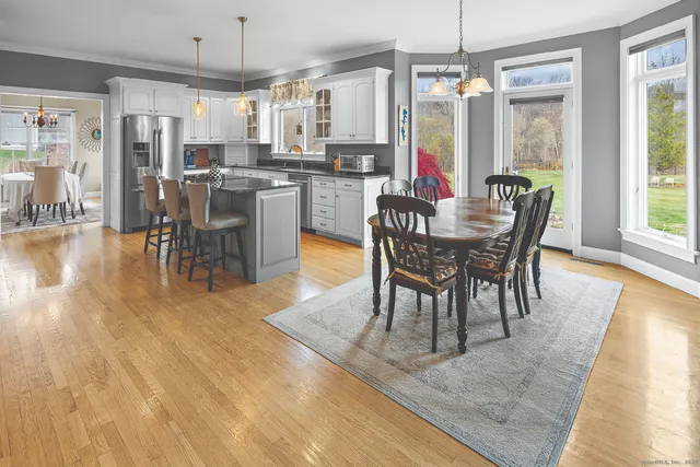 a dining room with stainless steel appliances granite countertop a table chairs and a view of living room