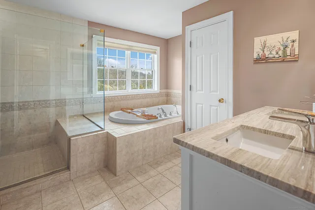 a bathroom with a granite countertop sink and a bathtub