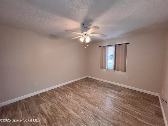 a view of an empty room with window and wooden floor
