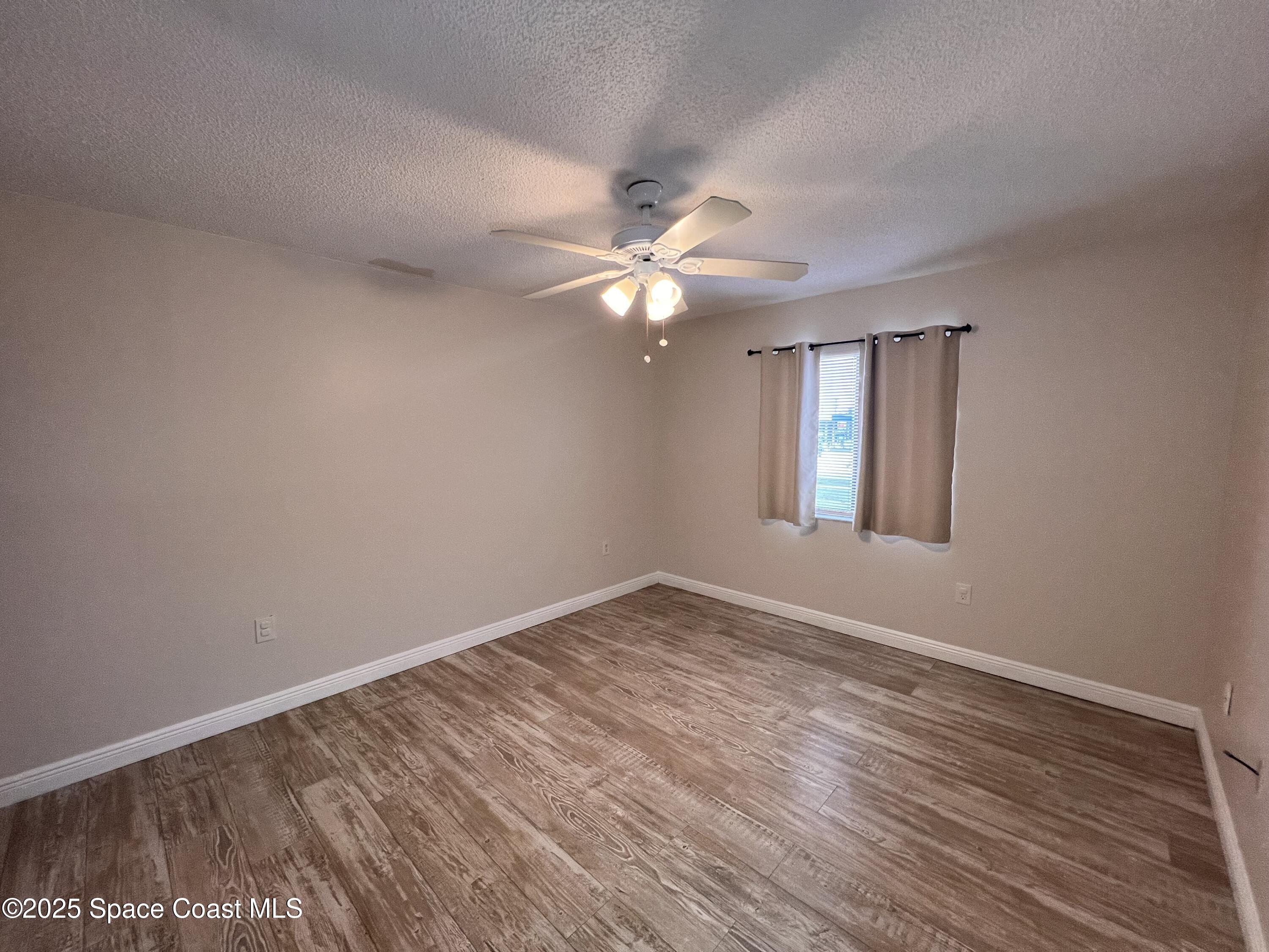 217 San Juan Circle Melbourne, FL 32935 - Photo 4 of 9 a view of an empty room with window and wooden floor