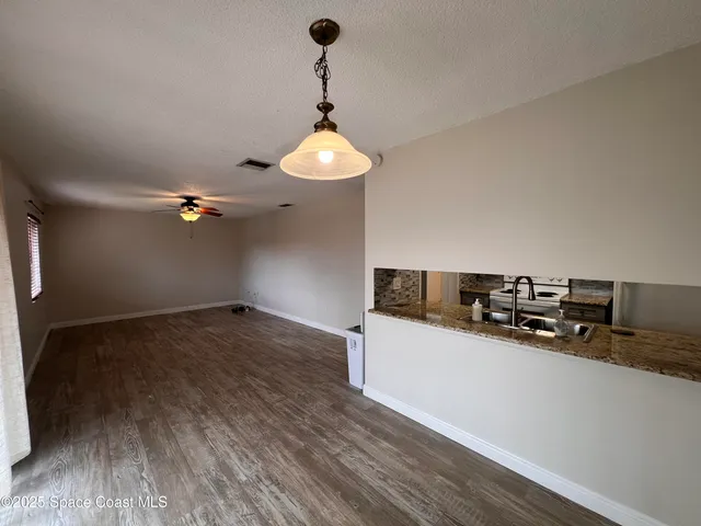 a kitchen with a sink a chandelier stainless steel appliances and cabinets