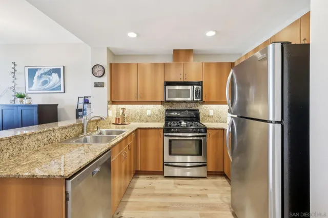 a kitchen with stainless steel appliances granite countertop a refrigerator a stove top oven a sink and dishwasher