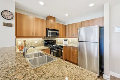 a kitchen with stainless steel appliances a refrigerator a sink dishwasher a dining table and chairs with wooden floor