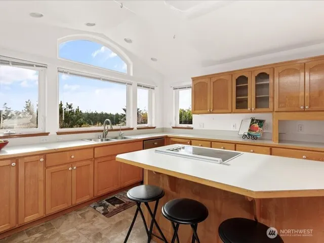 a kitchen with a sink a window and chairs