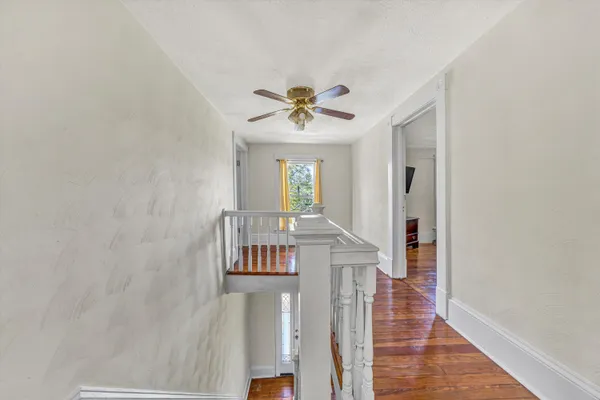 a view of an empty room with wooden floor and windows