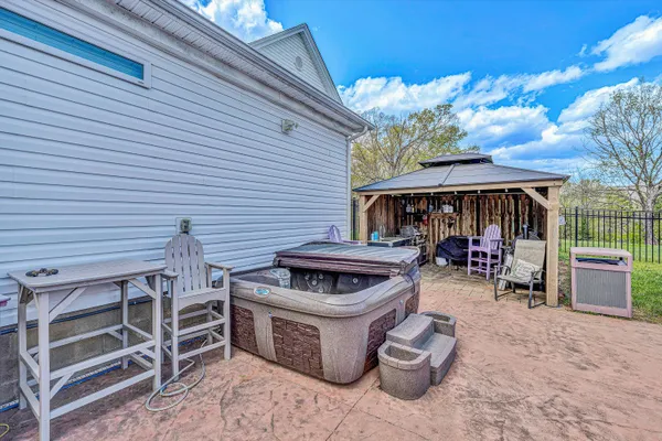 a view of a backyard with table and chairs potted plants and large tree