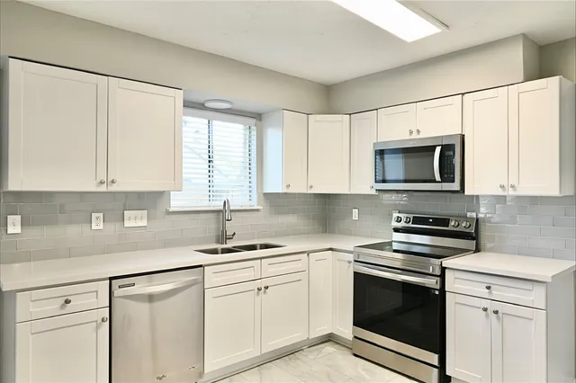 a kitchen with white cabinets and white appliances