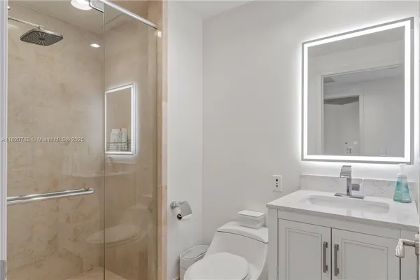 a bathroom with a toilet a sink a glass door a shower and a mirror