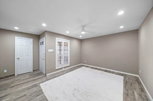 an empty room with wooden floor and windows
