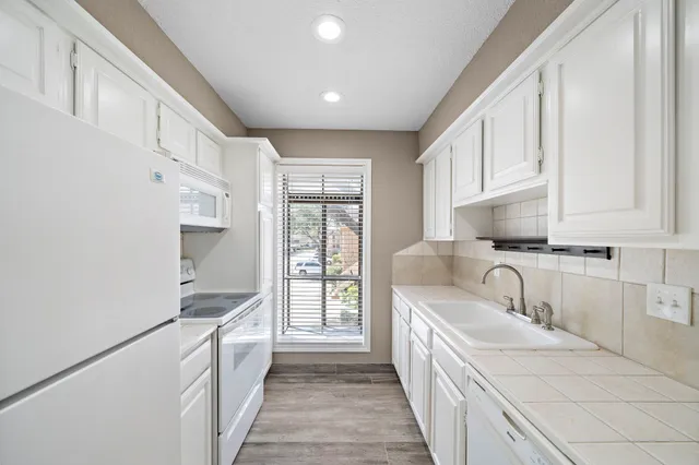 a kitchen with granite countertop a sink stove and cabinets