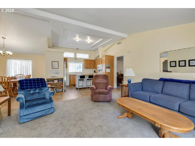 a living room with furniture kitchen view and a chandelier