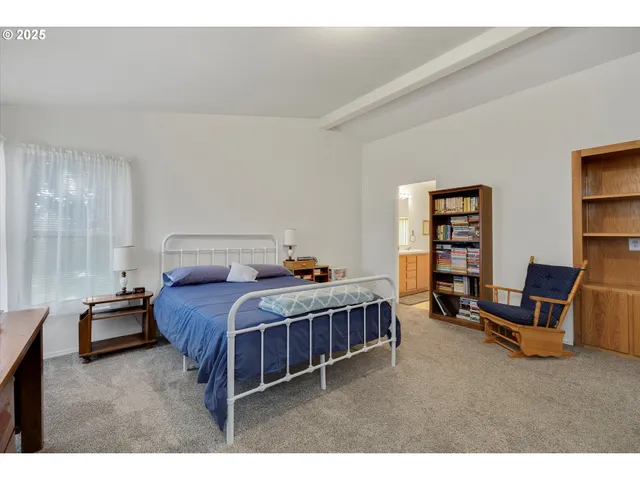 a bedroom with a bed a bookshelf and a chair