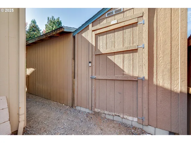 a view of a house with a wooden bench in a backyard