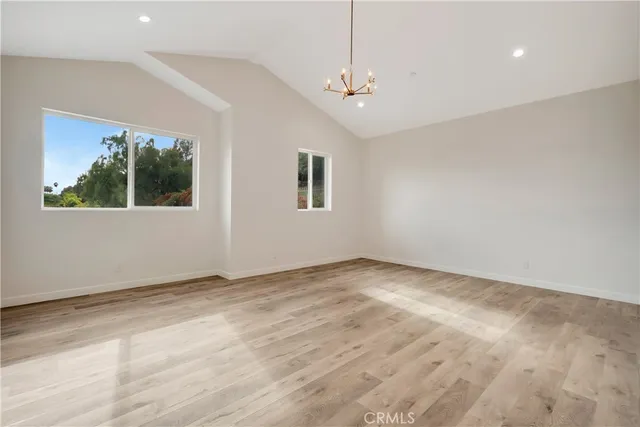 a view of an empty room with wooden floor and a ceiling fan