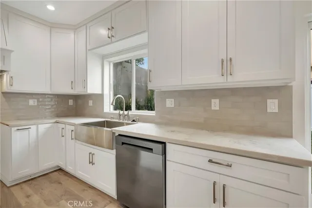 a kitchen with stainless steel appliances granite countertop a sink and dishwasher with white cabinets