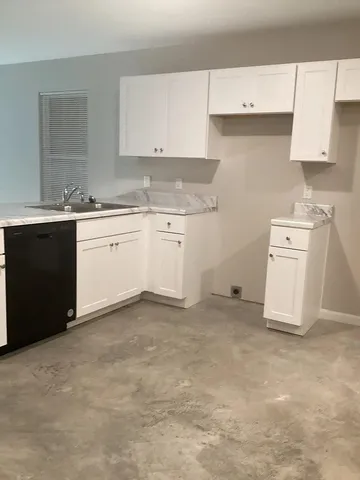 a kitchen with granite countertop a sink stove and cabinets