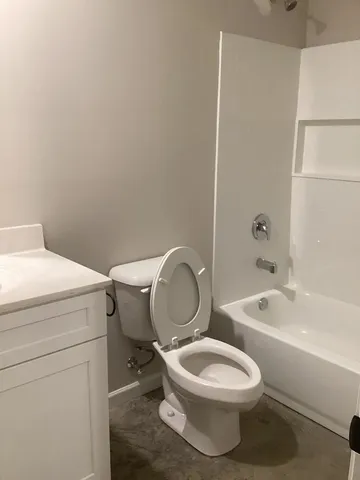 a white toilet sitting next to a bathroom sink and vanity