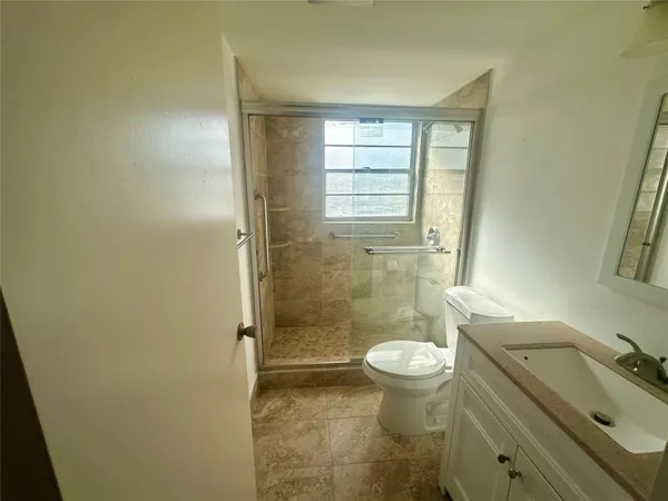 a bathroom with a granite countertop toilet a sink and a shower