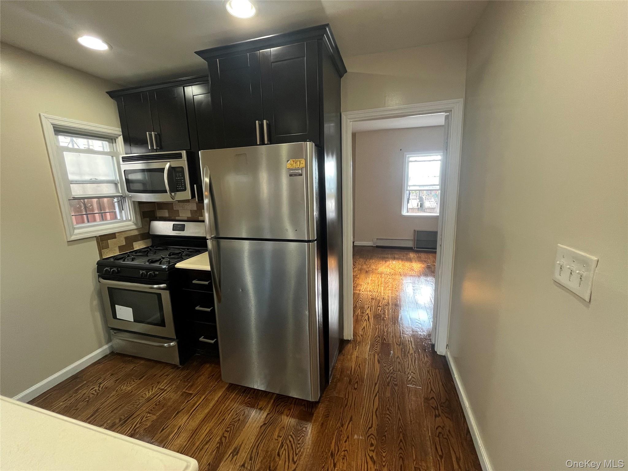 168-28 106th Avenue, Unit 1 Queens, NY 11433 - Photo 11 of 13 a kitchen with kitchen island wooden floor appliances and refrigerator