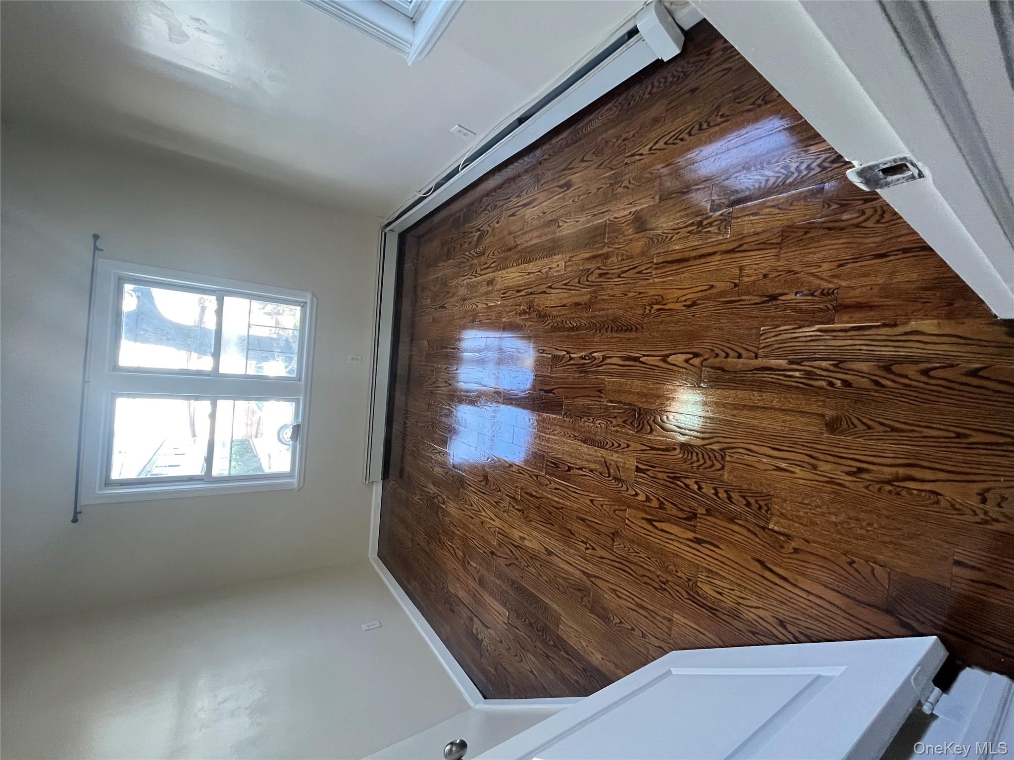 168-28 106th Avenue, Unit 1 Queens, NY 11433 - Photo 6 of 13 a view of empty room with wooden floor and fan
