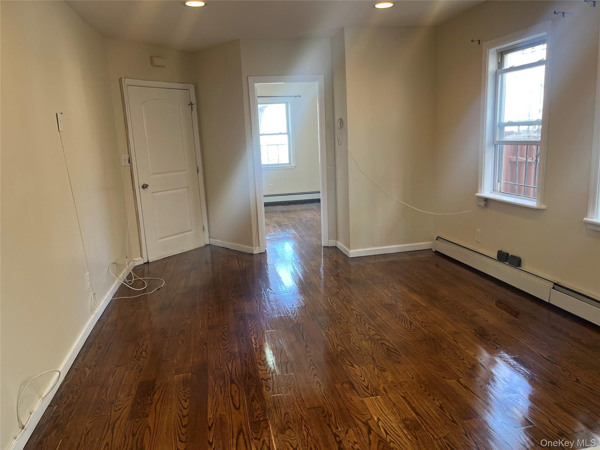 168-28 106th Avenue, Unit 1 Queens, NY 11433 - Photo 8 of 13 an empty room with wooden floor and windows
