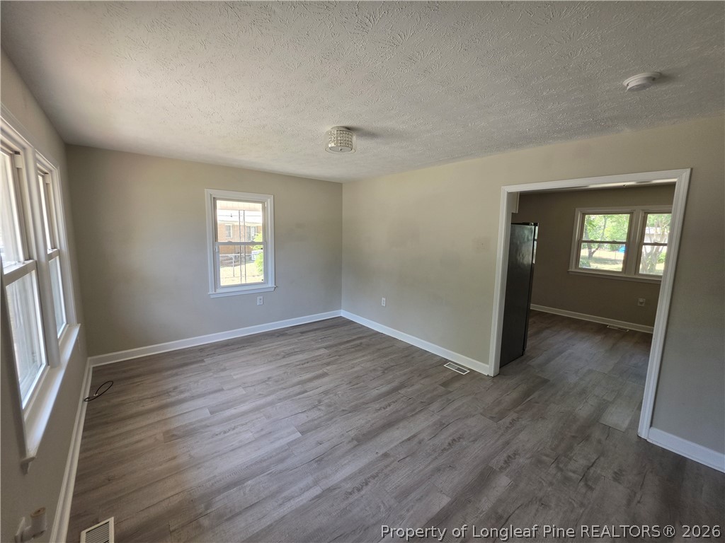 220 Cecil Avenue Spring Lake, NC 28390 - Photo 6 of 21 an empty room with wooden floor and windows