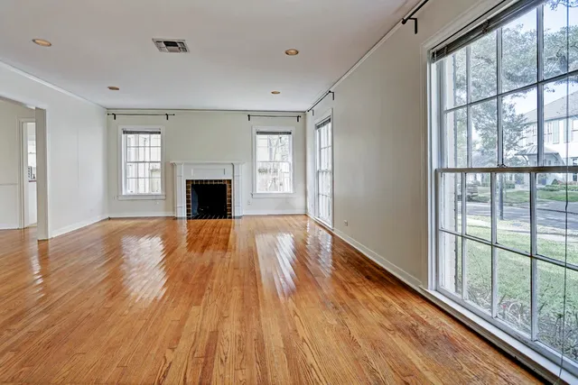 a view of an empty room with wooden floor fireplace and a window