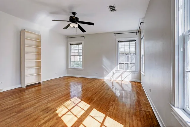 a view of empty room with wooden floor and fan