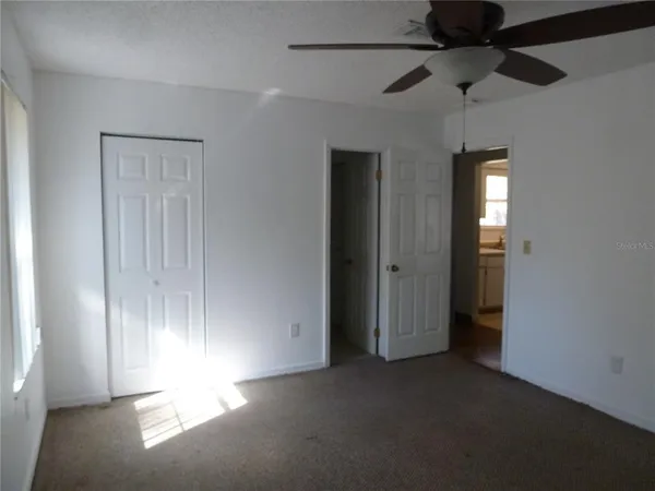 an empty room with windows and fan