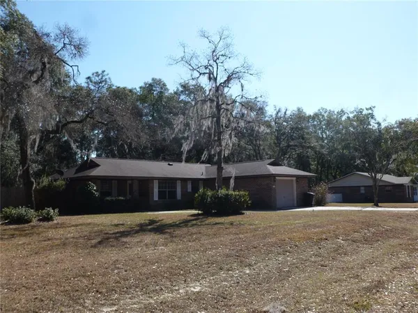 a front view of house with yard and trees in the background