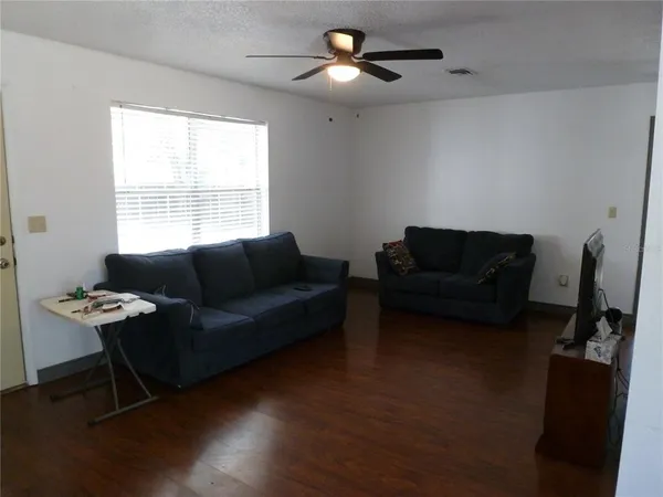 a living room with furniture a ceiling fan and a window