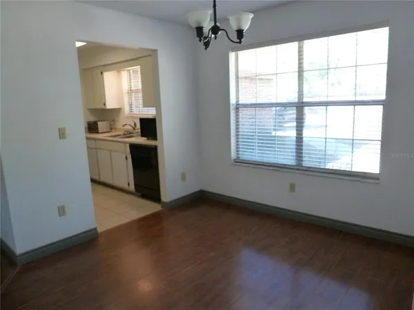 a view of a kitchen and an empty room with a window
