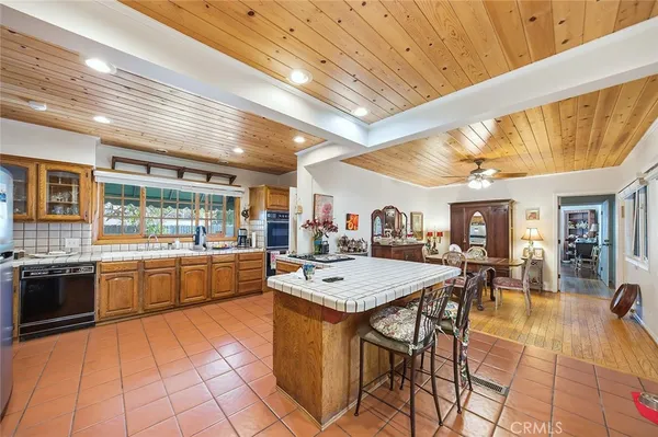 a kitchen with stainless steel appliances granite countertop a stove a sink a dining table and chairs with the wooden floor