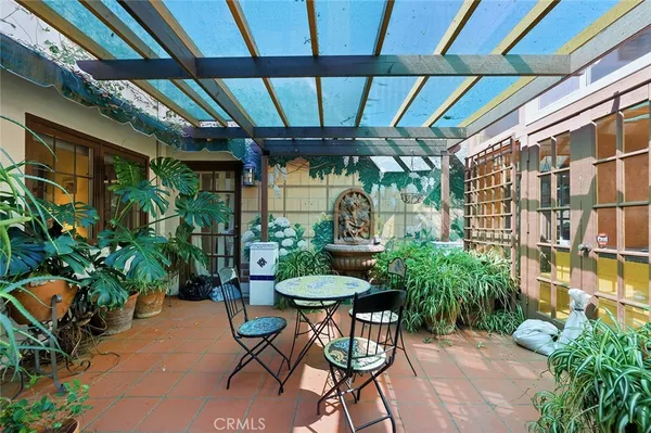 a patio with a table and chairs and potted plants