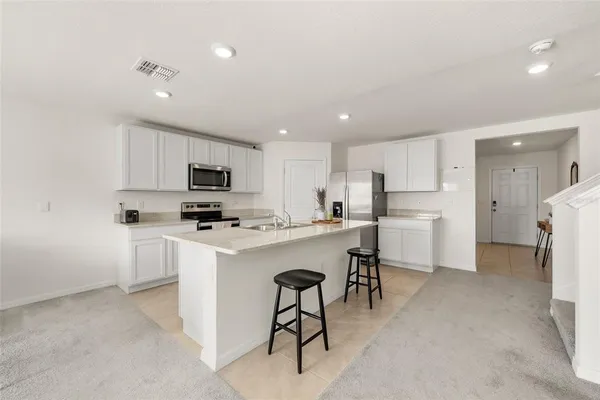 a kitchen with a refrigerator a microwave oven a sink dishwasher with a dining table and chairs