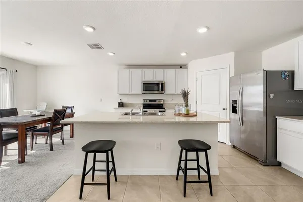 a kitchen with stainless steel appliances granite countertop a refrigerator a stove a sink a dining table and chairs with wooden floor