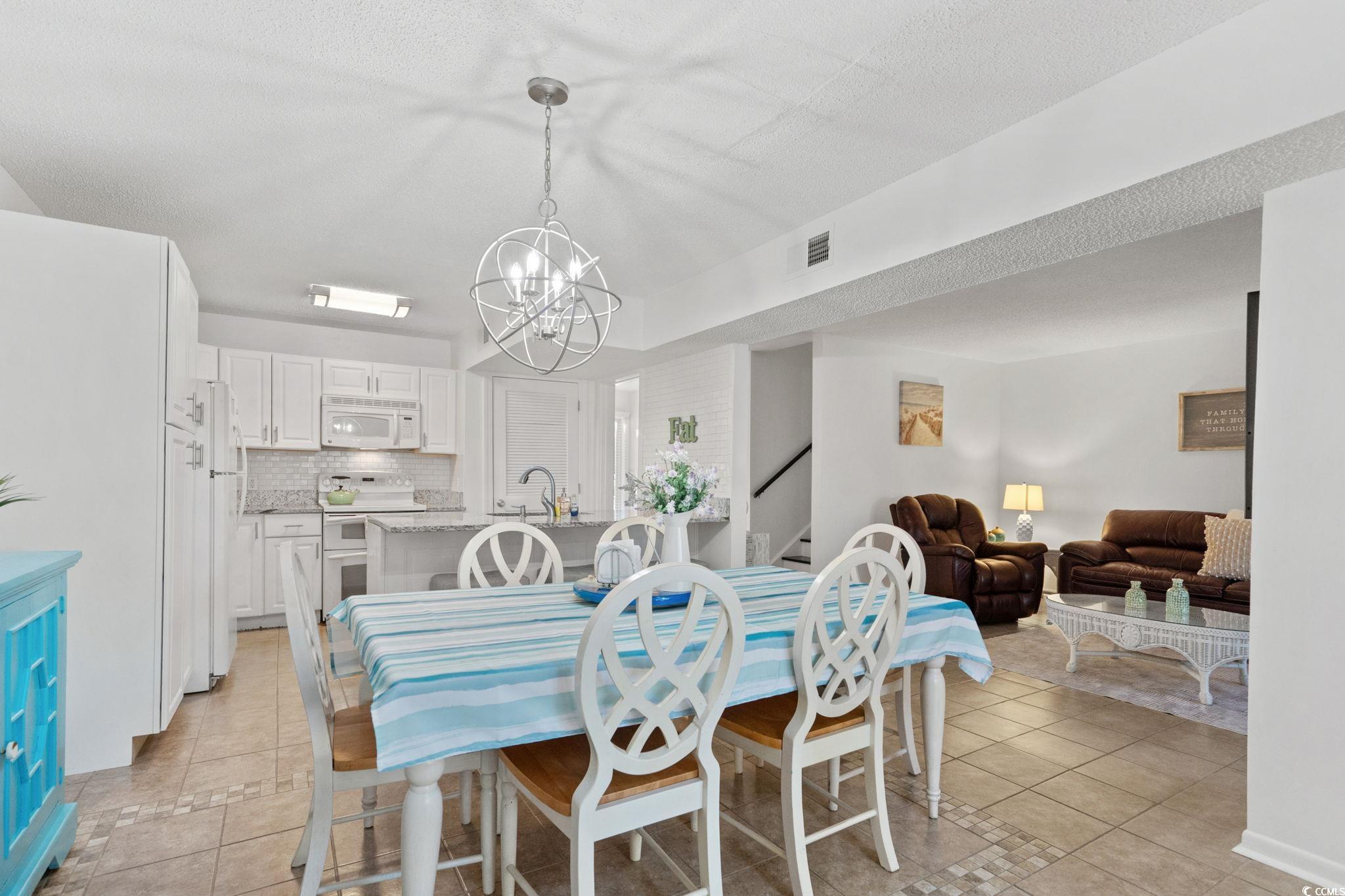 500 Eagle Way, Unit 6 Little River, SC 29566 - Photo 5 of 38 Dining area with light tile patterned flooring, a chandelier, stairs, and a textured ceiling