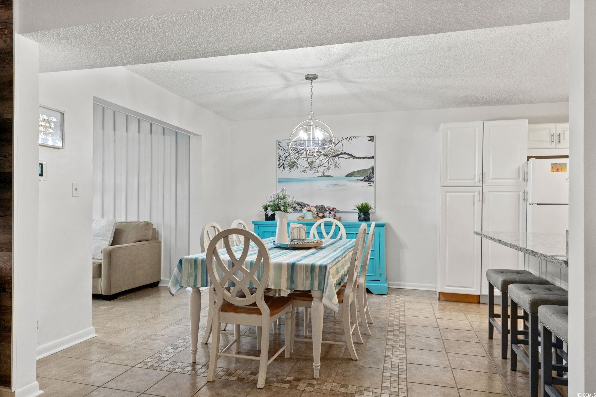 500 Eagle Way, Unit 6 Little River, SC 29566 - Photo 6 of 38 Dining room featuring inlaid floor details, light tile patterned floors, a textured ceiling, and a chandelier
