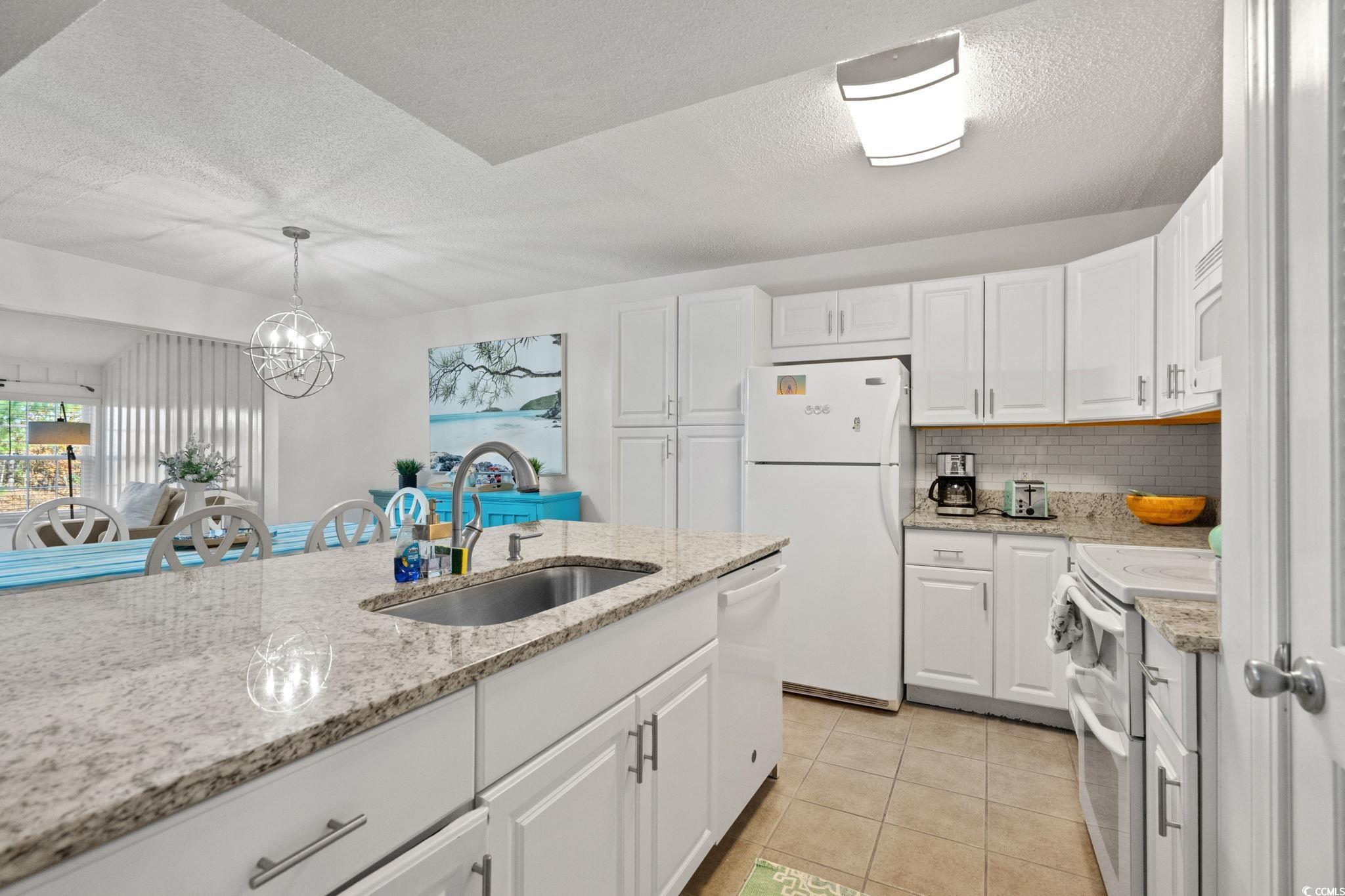 500 Eagle Way, Unit 6 Little River, SC 29566 - Photo 9 of 38 Kitchen featuring white cabinets, white appliances, light tile patterned flooring, light stone countertops, and tasteful backsplash