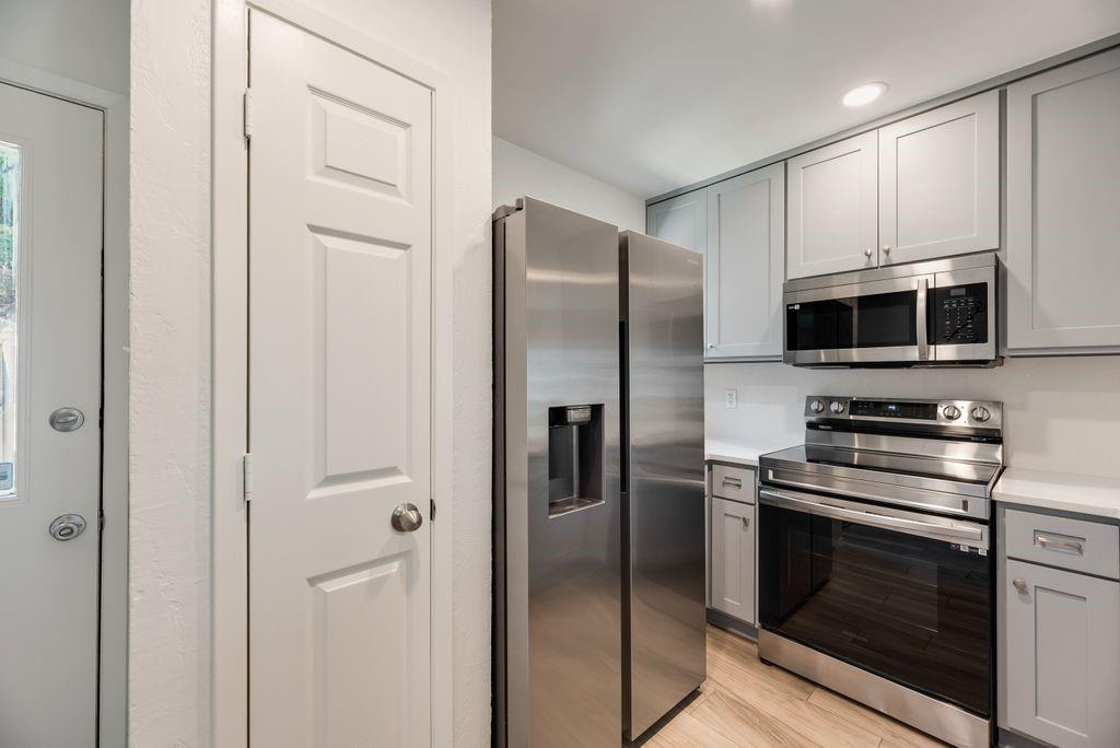 28 Abbey Road Euless, TX 76039 - Photo 8 of 19 Contemporary kitchen featuring stainless steel appliances, light gray cabinetry, white countertops, and wood-finish flooring