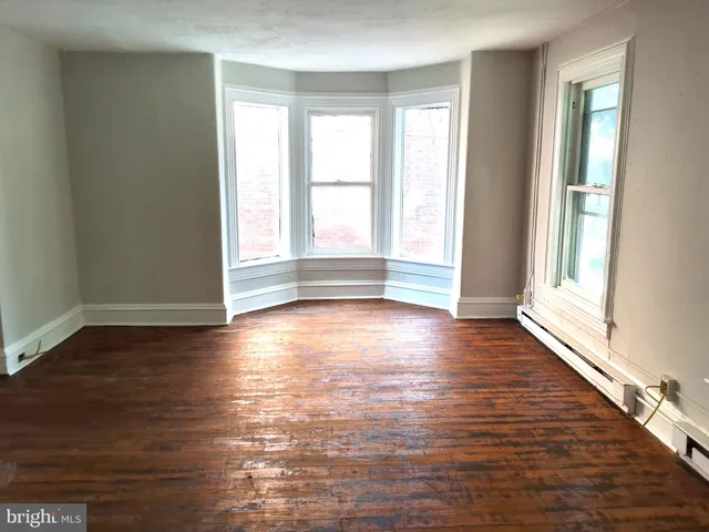 an empty room with wooden floor and windows with curtains view
