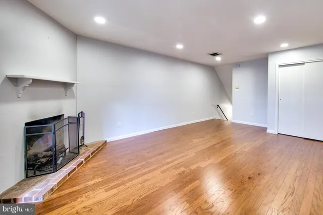 a view of empty room with wooden floor and fireplace