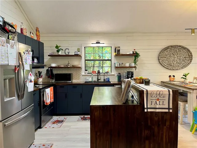 a kitchen with kitchen island granite countertop a sink stove and refrigerator