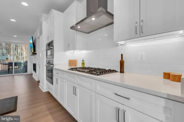 a kitchen with stainless steel appliances kitchen island granite countertop a table chairs sink and cabinets
