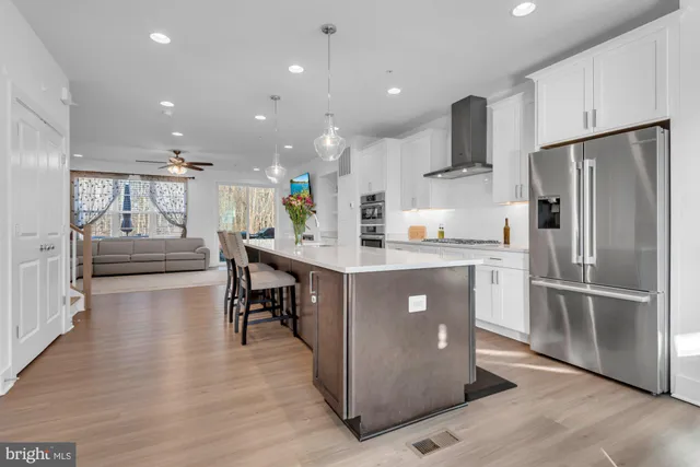 a kitchen with a table chairs wooden floors and a view of living room