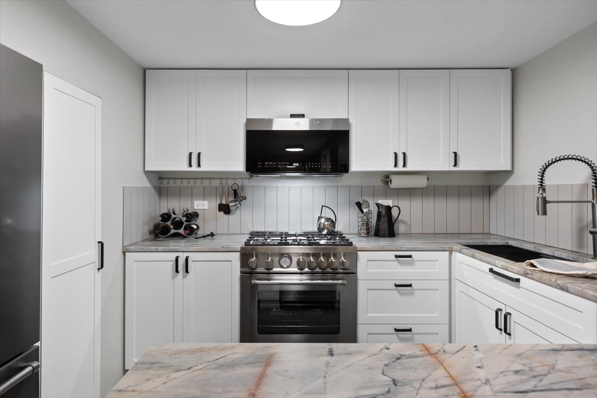 159 West Burton Place, Unit G Chicago, IL 60610 - Photo 16 of 37 a kitchen with granite countertop a stove a sink and a microwave
