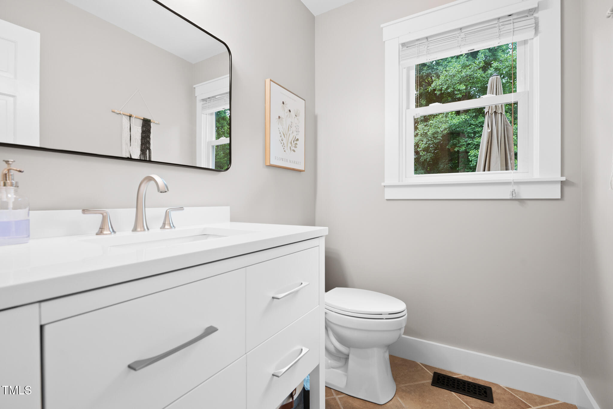 8608 Valley Brook Drive Raleigh, NC 27613 - Photo 22 of 74 a bathroom with a toilet a sink a window and a mirror