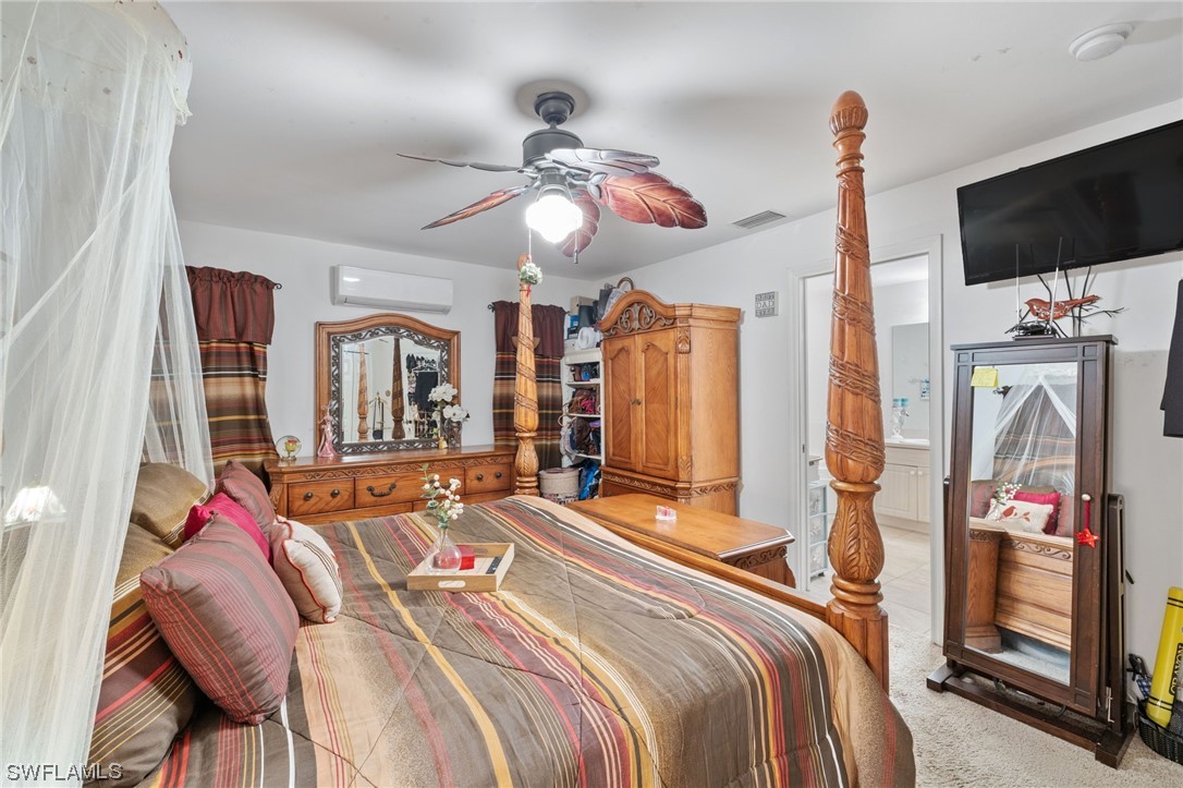 811 Abrams Boulevard Lehigh Acres, FL 33971 - Photo 11 of 22 a bedroom with bed a flat tv screen and a chandelier