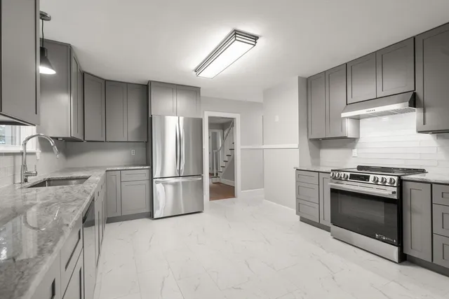 a kitchen with stainless steel appliances granite countertop a stove a refrigerator and a sink