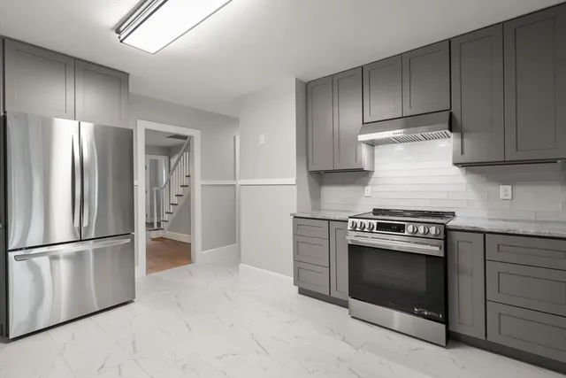 a kitchen with stainless steel appliances granite countertop a refrigerator and a stove top oven